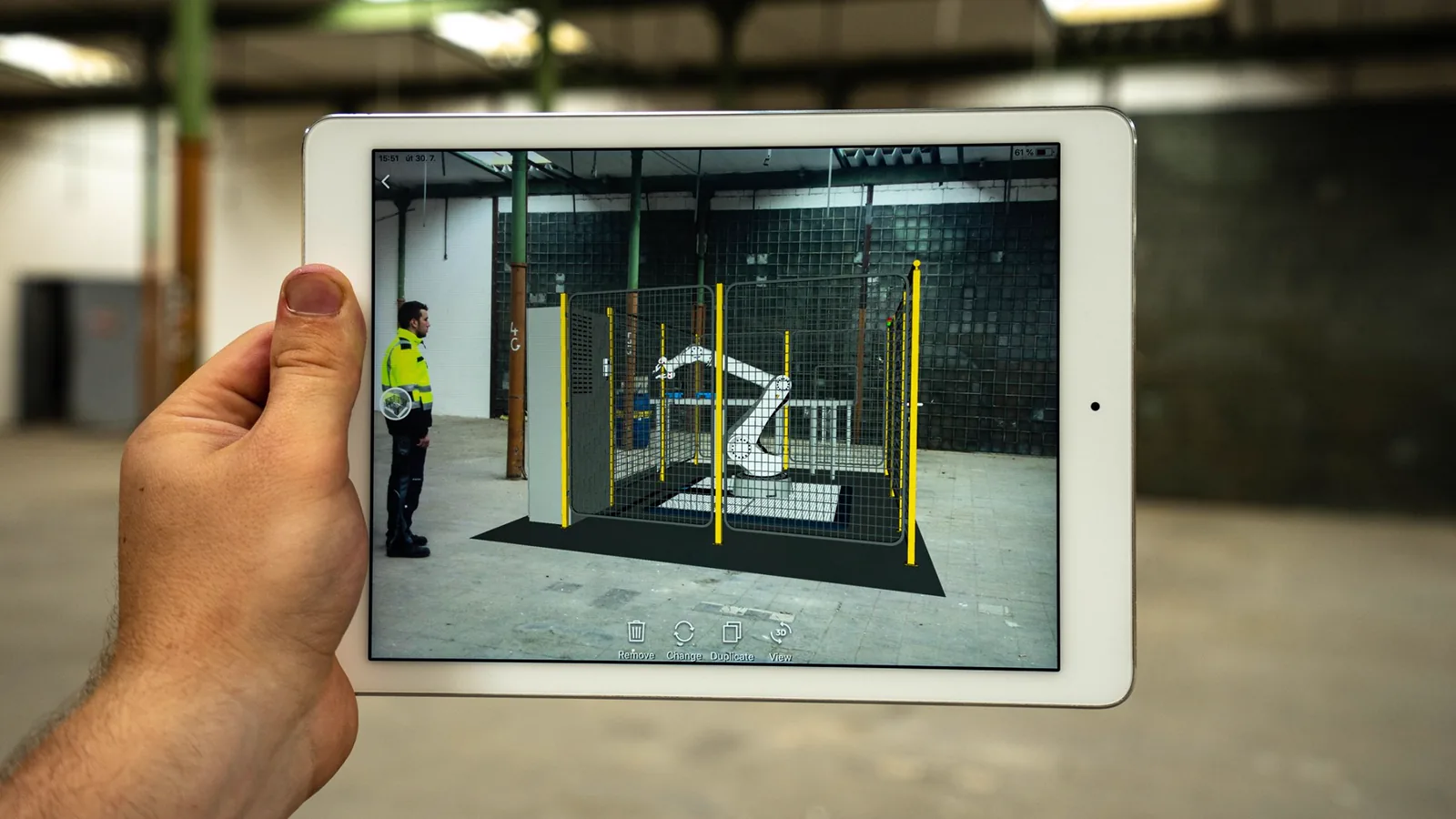 Tablet zeigt ein 3D-Modell einer geplanten Maschine in der bestehenden Halle